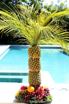 a pineapple palm tree sitting on top of a table next to a swimming pool