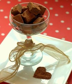 a glass bowl filled with brownies sitting on top of a white plate next to a red tablecloth