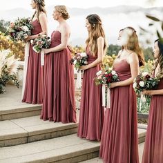 bridesmaids in red dresses standing on steps with their bouquets and looking at each other