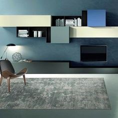 a modern living room with blue walls and grey carpeted flooring, built in shelving units