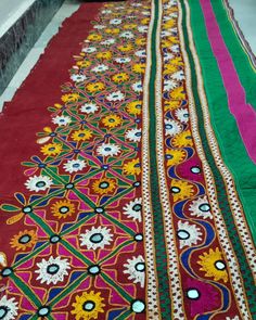 a red and green table runner with colorful designs on the edges, along with other decorative items