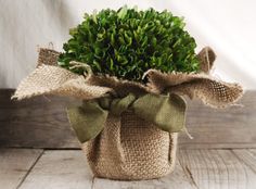 a burlock wrapped vase filled with greenery on top of a wooden table