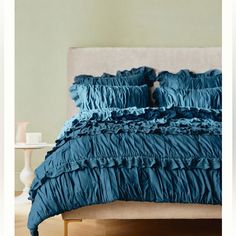 a bed with blue ruffled sheets and pillows