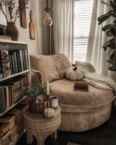 a living room filled with furniture and bookshelves next to a window covered in white curtains