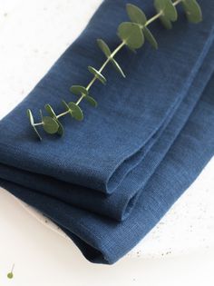 three pieces of blue cloth with green leaves on them sitting on a white table top