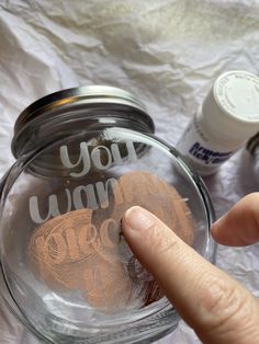 a hand is pointing at a jar with some writing on it