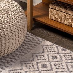 a gray and white rug sitting on top of a wooden floor next to a table