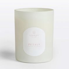 a white candle with a label on it that says petal's in pink lettering