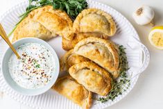 several pastries on a white plate with a bowl of dip