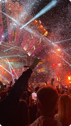 a crowd at a concert with confetti thrown in the air and lights on