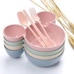 a set of four bowls with forks and spoons in them next to wheat stalks