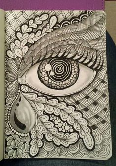 an eye is drawn on top of a book with swirls and leaves around it