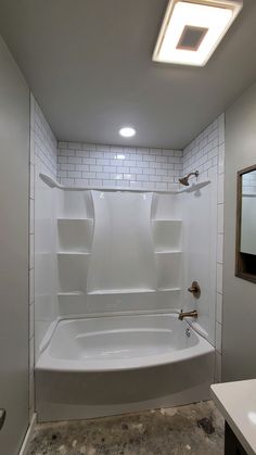 a bathroom with a bathtub, sink and mirror on the wall next to it