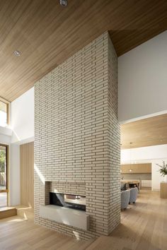 an empty living room with wood flooring and brick fireplace in the middle of it