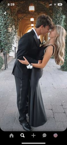 a man and woman standing next to each other in front of a building with ivy covered walls