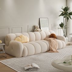 a white couch sitting on top of a wooden floor next to a table and potted plant