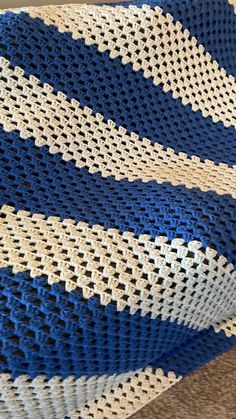 a blue and white crocheted blanket laying on the floor