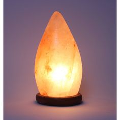 a himalayan stone lamp on a wooden base with a white light shining in the background