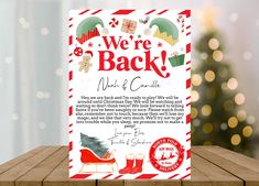 we're back work and christmas card on a wooden table with a christmas tree in the background