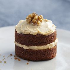 a chocolate cake with white frosting and walnuts on top is sitting on a plate