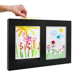 a hand is holding a piece of paper with flowers and birds on it, in front of a black frame