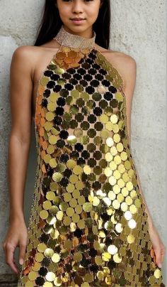 a woman in a gold sequin dress posing for the camera with her hands on her hips