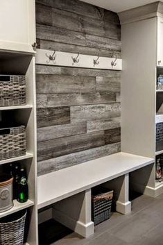 a laundry room with white cabinets and gray wood planks on the wall behind it