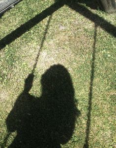 the shadow of a person holding a frisbee in their hand on some grass