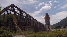 a woman standing in front of a train bridge