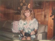 an old photo of a woman sitting on a couch with a camera in her hand