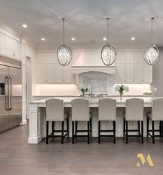 a large kitchen with white cabinets and marble counter tops, an island in the middle