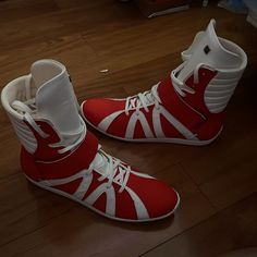 a pair of red and white shoes sitting on top of a wooden floor