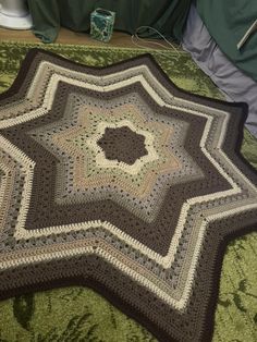 a crocheted blanket is laying on the floor next to a bed with green sheets