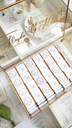 a display case filled with lots of white and gold wedding stationery on top of a table