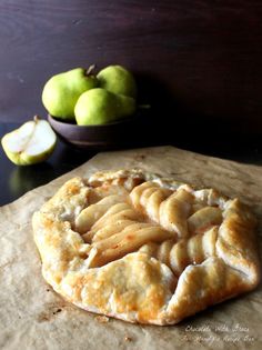 an apple pie on a piece of wax paper next to some apples