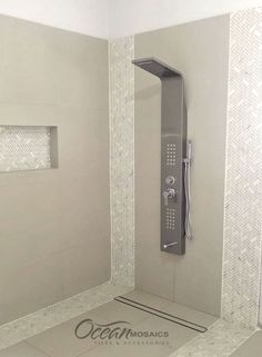 a shower head and hand shower in a bathroom with white tiles on the walls, along with an ocean mosaics logo