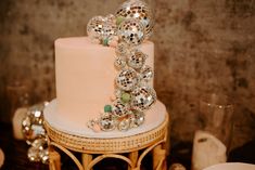 a pink cake with disco balls on top sitting on a table next to other decorations