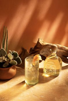 a bottle of alcohol sitting next to a glass with an orange peel in it on a table