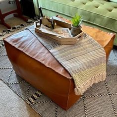 a leather ottoman sitting on top of a rug next to a green couch