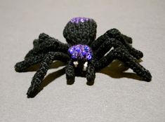 a purple and black spider sitting on top of a table