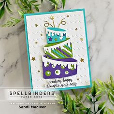 a card with a cake on it and green leaves in the background that says spellbinders