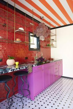 a kitchen with an island and purple cabinets in the center, surrounded by black and white tile flooring