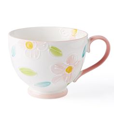 a white cup with flowers painted on the side and pink rim, sitting against a white background