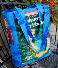 a blue bag sitting on top of a metal chair next to flowers and a book