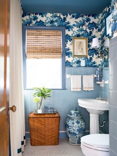 the bathroom is decorated in blue and white with flowers on the shower curtain, bamboo shades