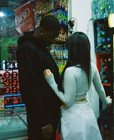 a man and woman standing next to each other in front of a vending machine