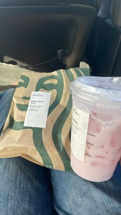 a plastic cup sitting on top of a person's lap next to a bag