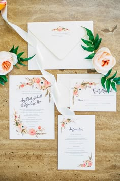 the wedding stationery is laid out with flowers and greenery