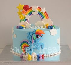 a blue cake decorated with rainbows and clouds