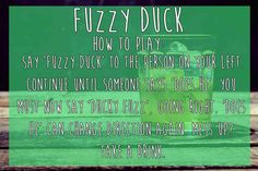 a glass filled with green liquid sitting on top of a wooden table next to a sign that reads fuzzy duck how to play